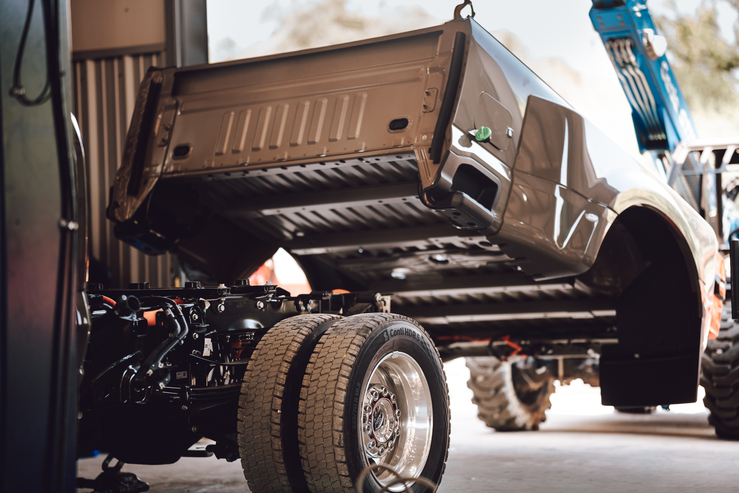 Truck bed being lifted from a truck chassis in the installation shop